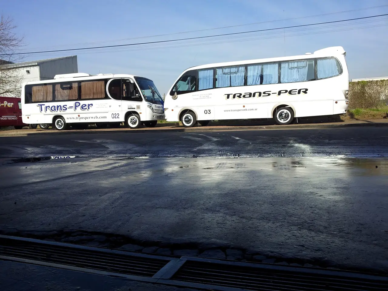 Dos minibuses de Trans-Per estacionados sobre el asfalto mojado